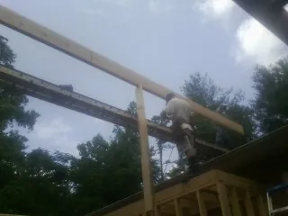 Carpenter setting a ridge beam over a new addition frame — Ice Dam Removal by Roofing Brothers in Braselton