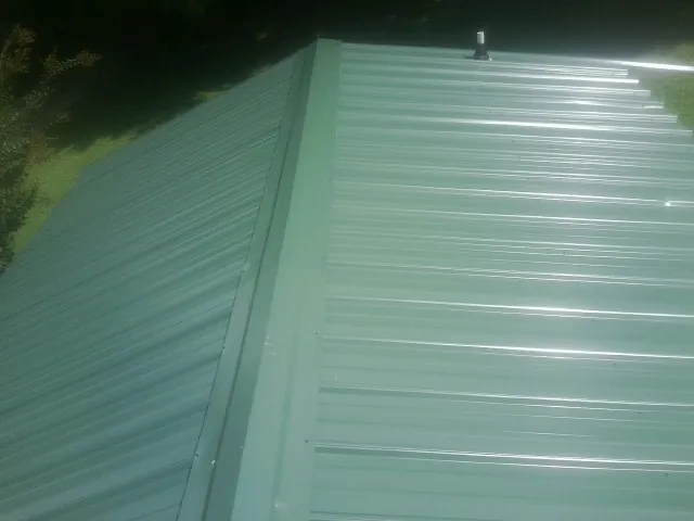 New green metal panels meeting at the ridge of a roof — Flat Roof Repair work by our crew in Braselton