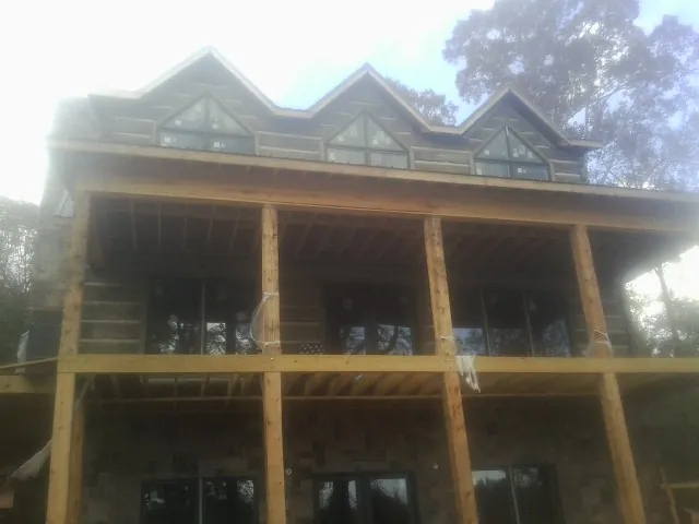 Dormers and porch framing on a large log home under construction — Roof Coating work by our crew in Braselton