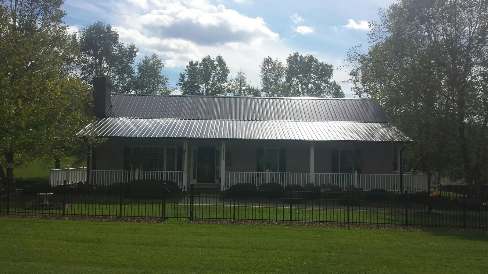 Gray metal roof on a brick ranch with a full width front porch — Gutter Guard Installation work by our crew in Braselton