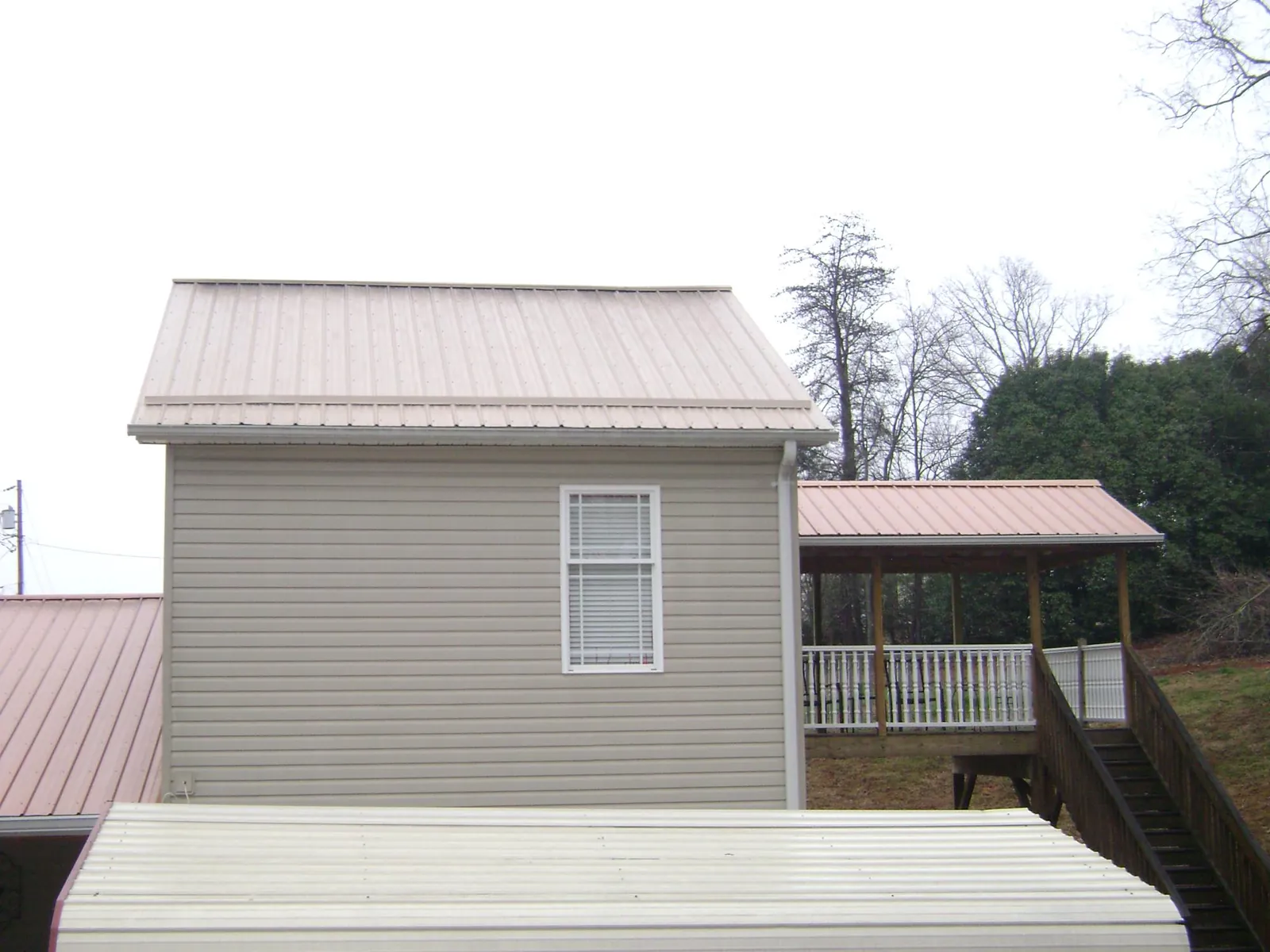 Tan metal roofs on a two story addition and attached porch, from a Roof Replacement job in Braselton