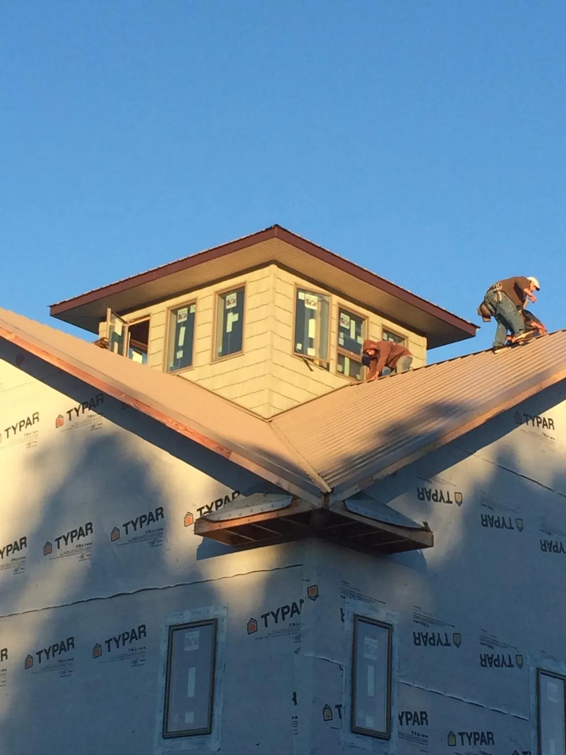 Roofers working around a rooftop cupola on a new metal roof at sunset — Roof Waterproofing in Braselton by Roofing Brothers
